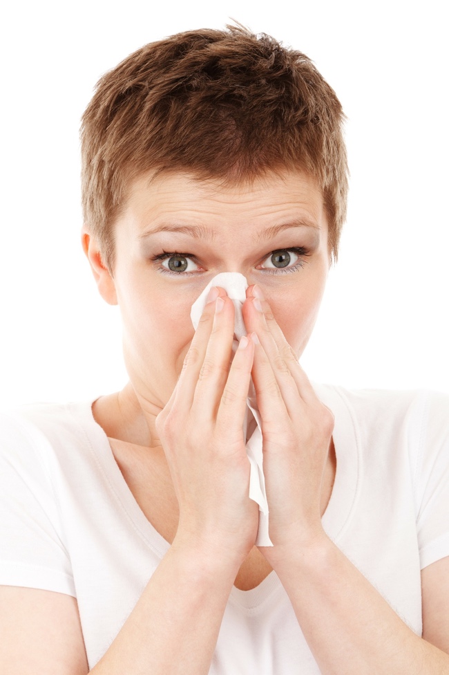 Woman with allergies blowing nose
